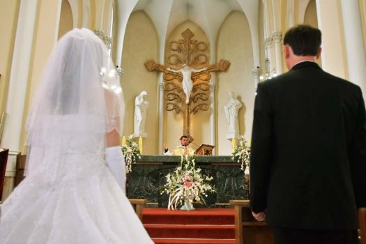 жених и невеста у алтаря в католической церкви на венчании