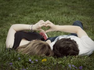 молодые люди на траве, из рук показывают сердечко