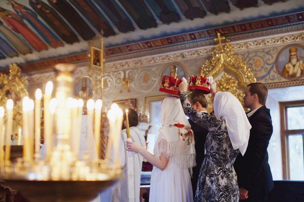 молодая пара на венчании в церкви, свидетели держат короны над их головами